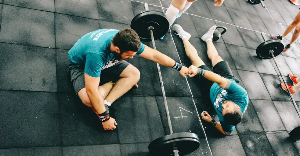 Two men sitting on the gym floor.