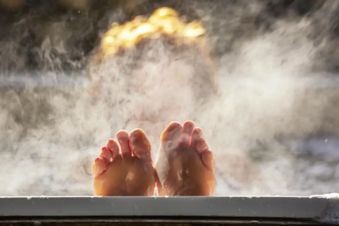 "Feet of a person sticking out from one end of a hot tub