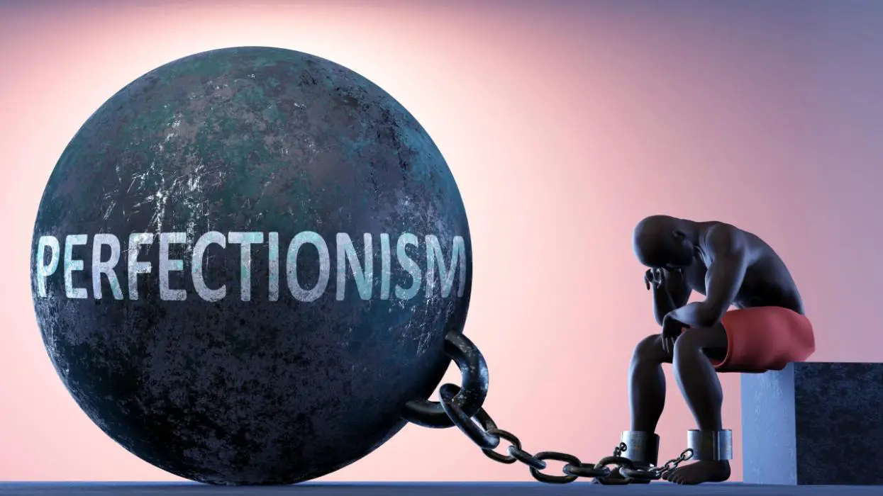 A depiction of a man constrained and shackled by the chains of perfectionism.
