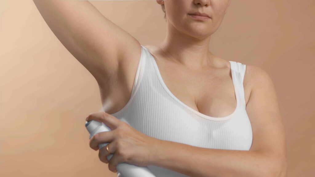 Women is spraying her arms and wearing a underwire bra 