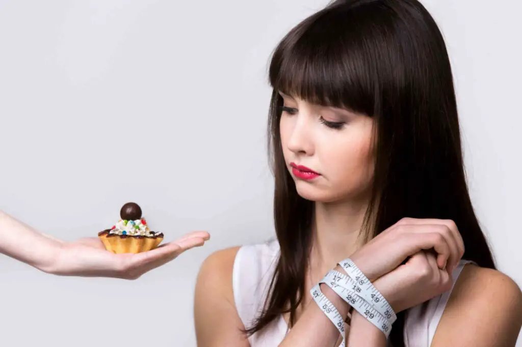 Women stopping herself from eating cupcake 