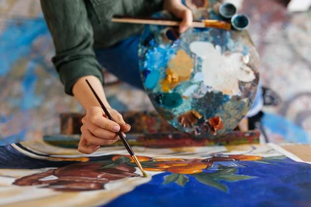 Overhead view of a woman painting while holding a color mixing tray