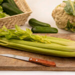 top view of celery on wooden board and knife