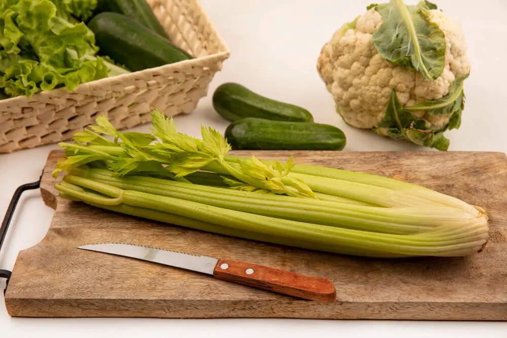 top view of celery on wooden board and knife 