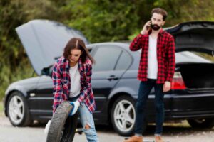 woman holding spare tire man talkin phone