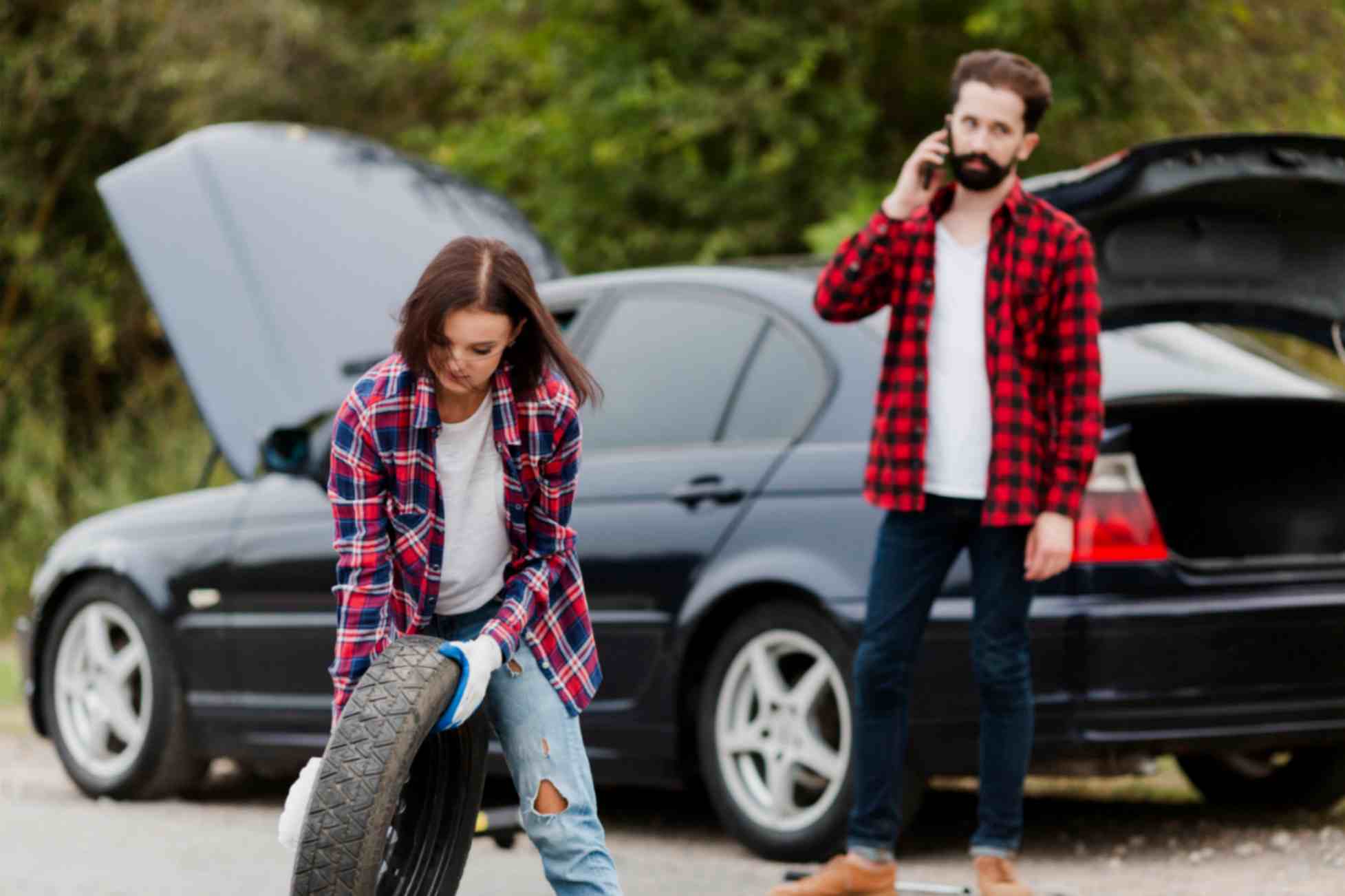 woman holding spare tire man talkin phone