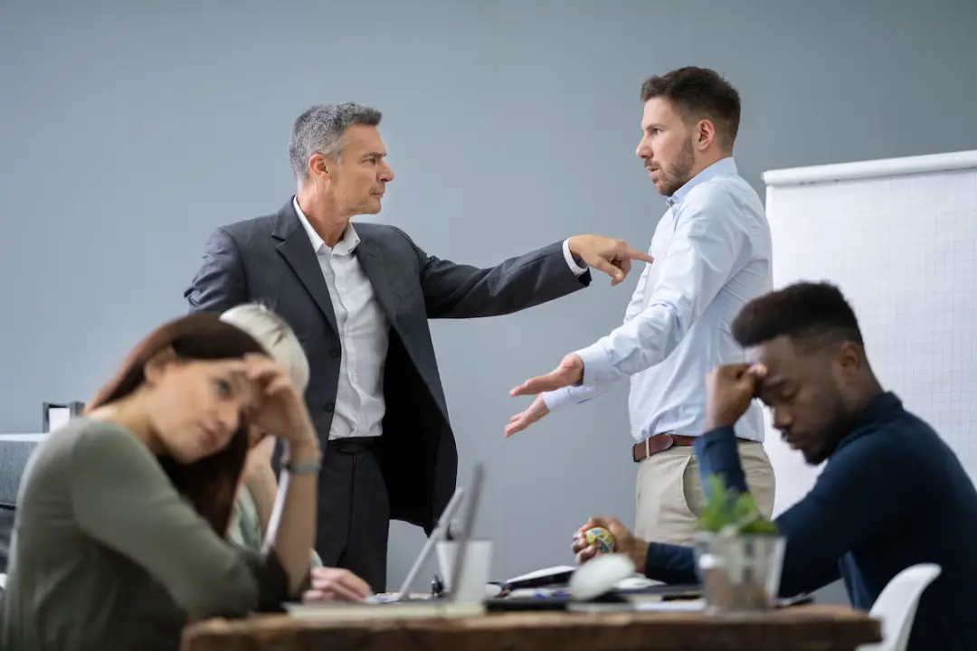 A supervisor scolding and mistreating an employee, surrounded by visibly disheartened colleagues...