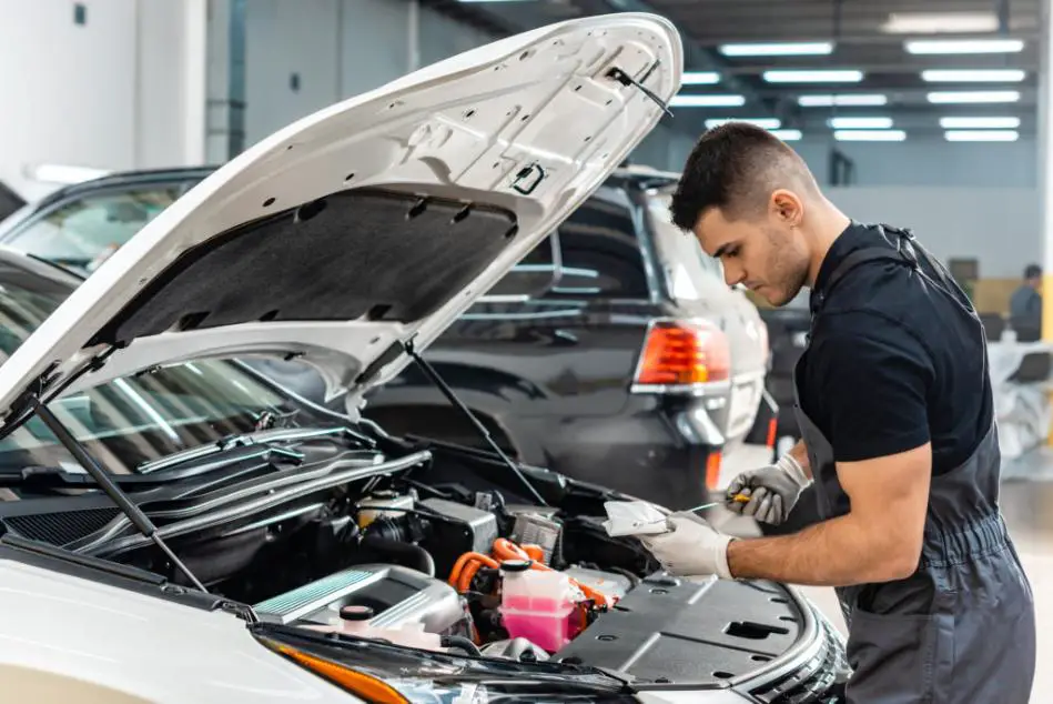 A mechanic inspecting the car with a focused gaze under the hood