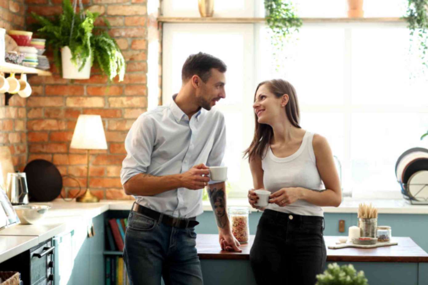 A couple talking to each other standing in the kitchen
