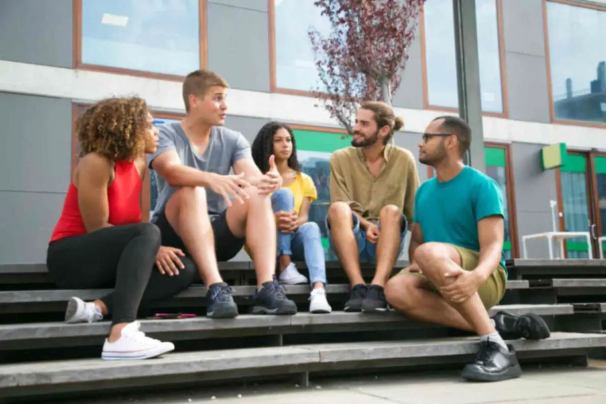 A group of frfiends talking to each other while sitting on a stair case