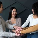 A group of friends standing with their hands stacked on each other's hands