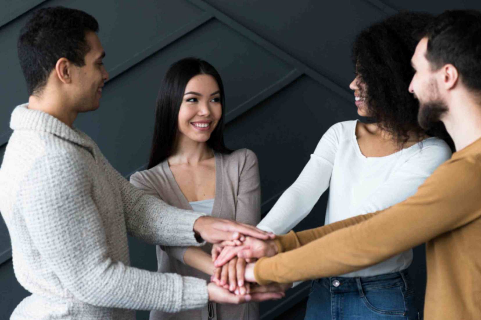 A group of friends standing with their hands stacked on each other's hands