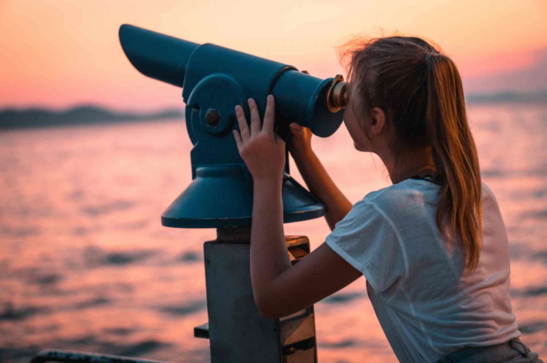 Female using telescope, looking into sunset at the beach.jpg