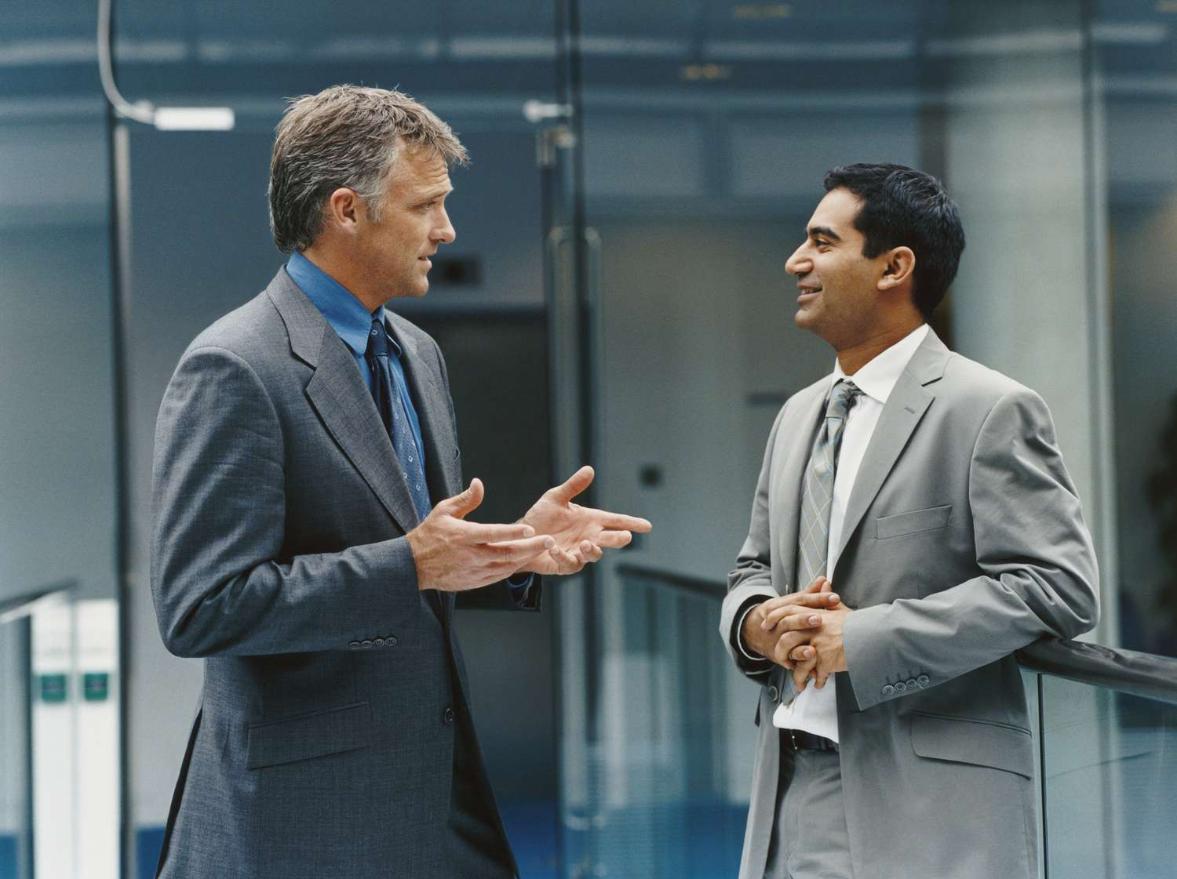 Two businessmen in professional attire engaged in discussion.