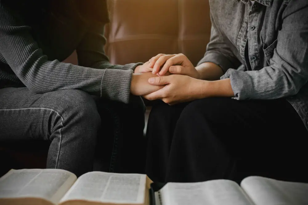 A man gently holding a girl's hands, their heads out of view.