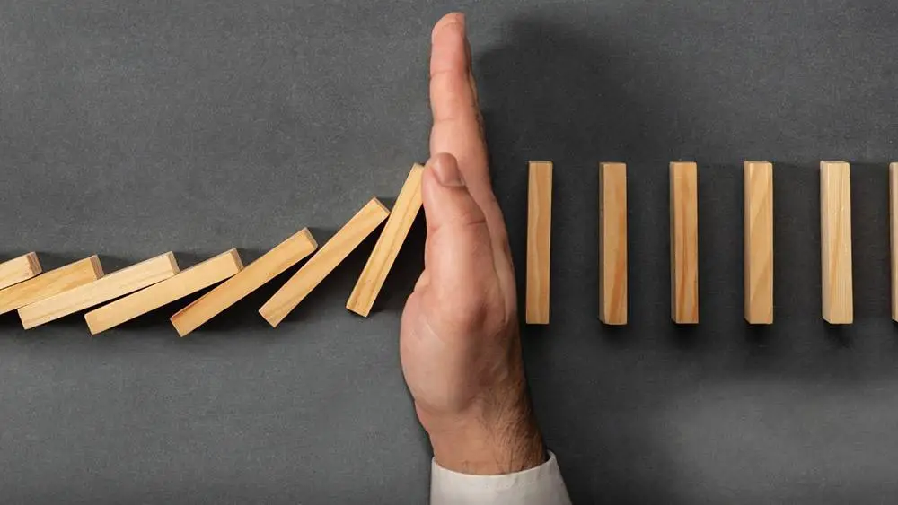 Healthy Boundaries and Assertiveness Demonstrated by a Hand Stopping Wooden Squares from Toppling Over