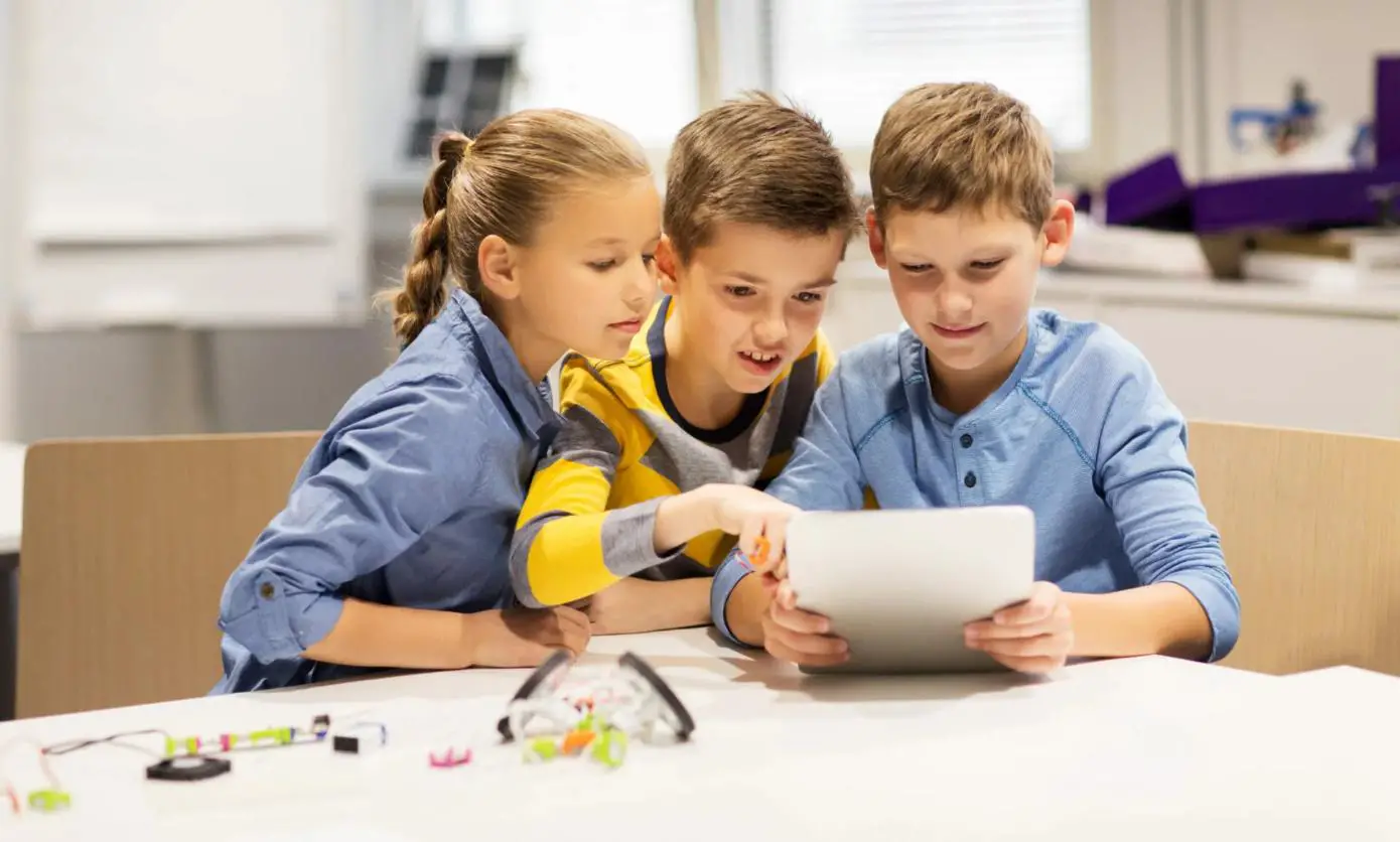 Three Children are Engaged in Discussion Over Content on a Tablet