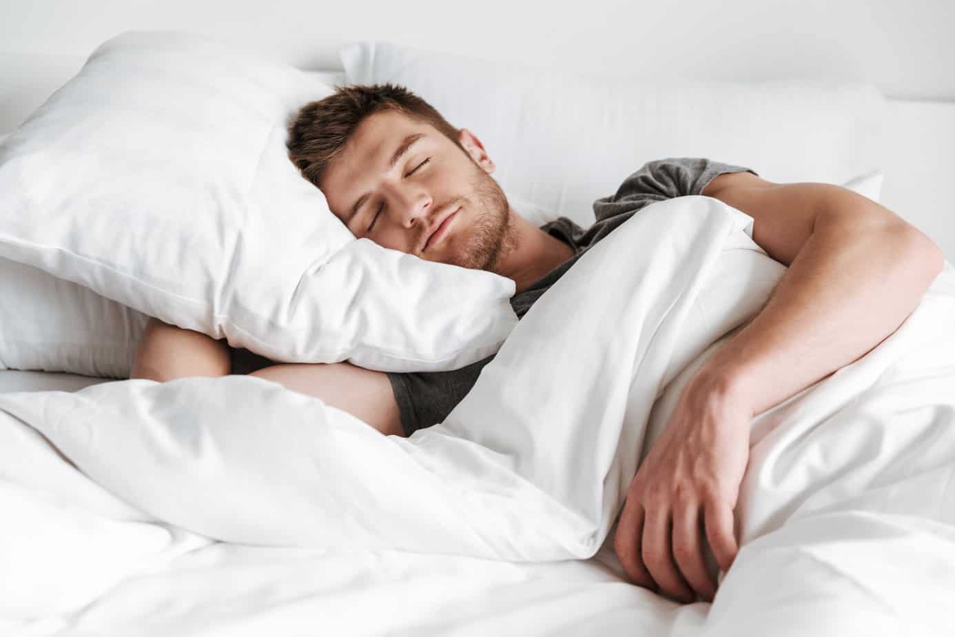 A man lying in bed with closed eyes, appearing calm and serene