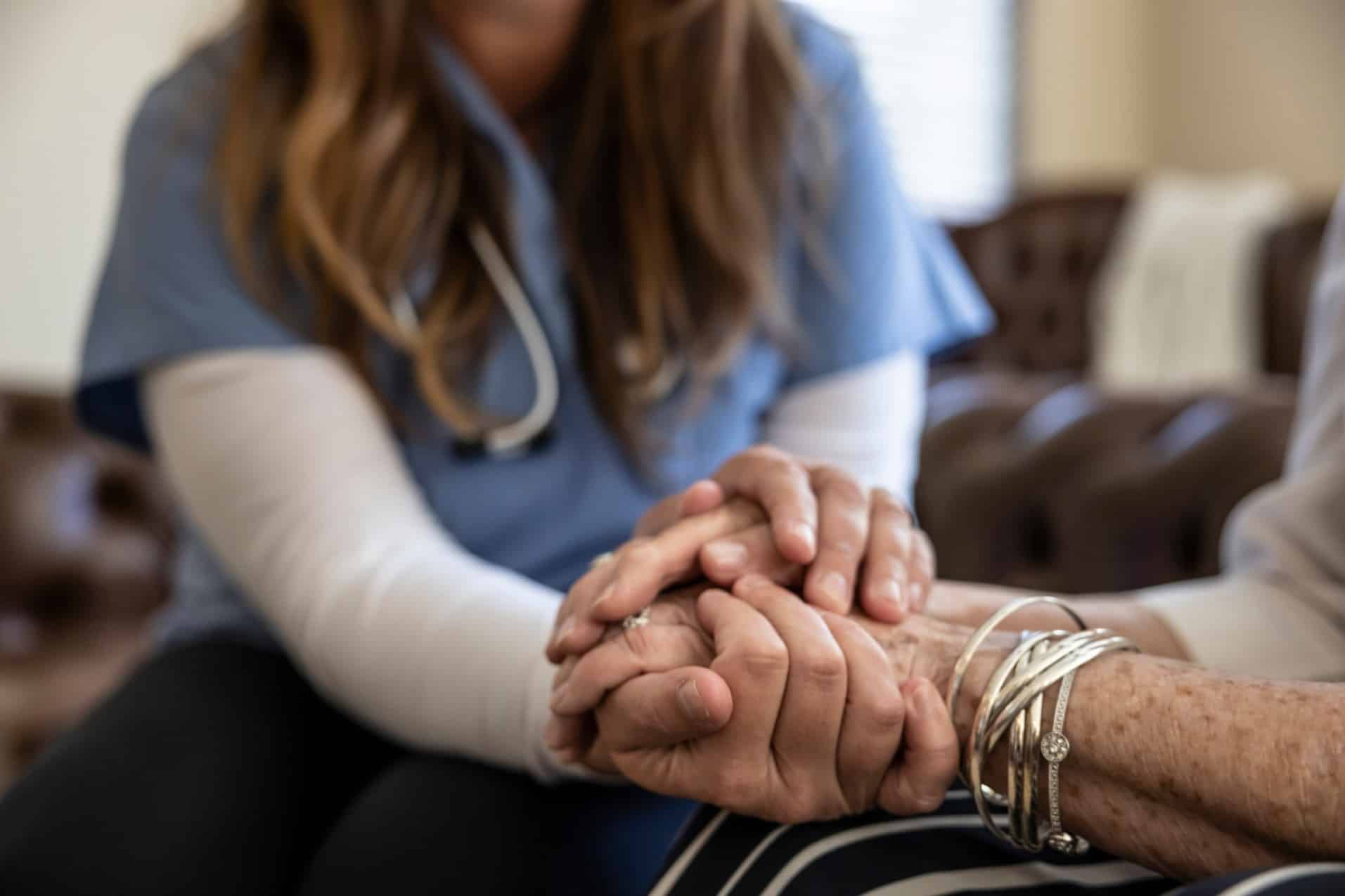 A nurse and patient joined hands, demonstrating compassion and support.