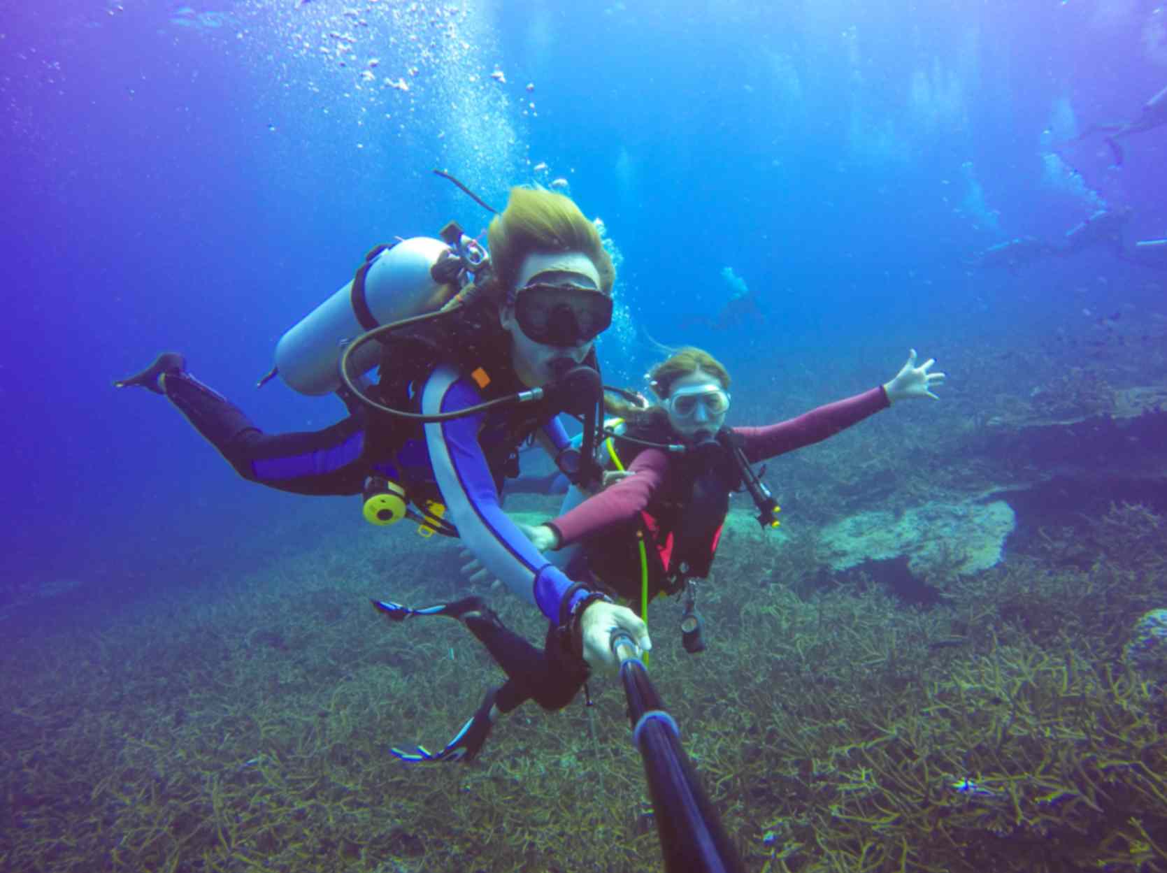 Two girls underwater scuba-diving selfie shot with selfie stick