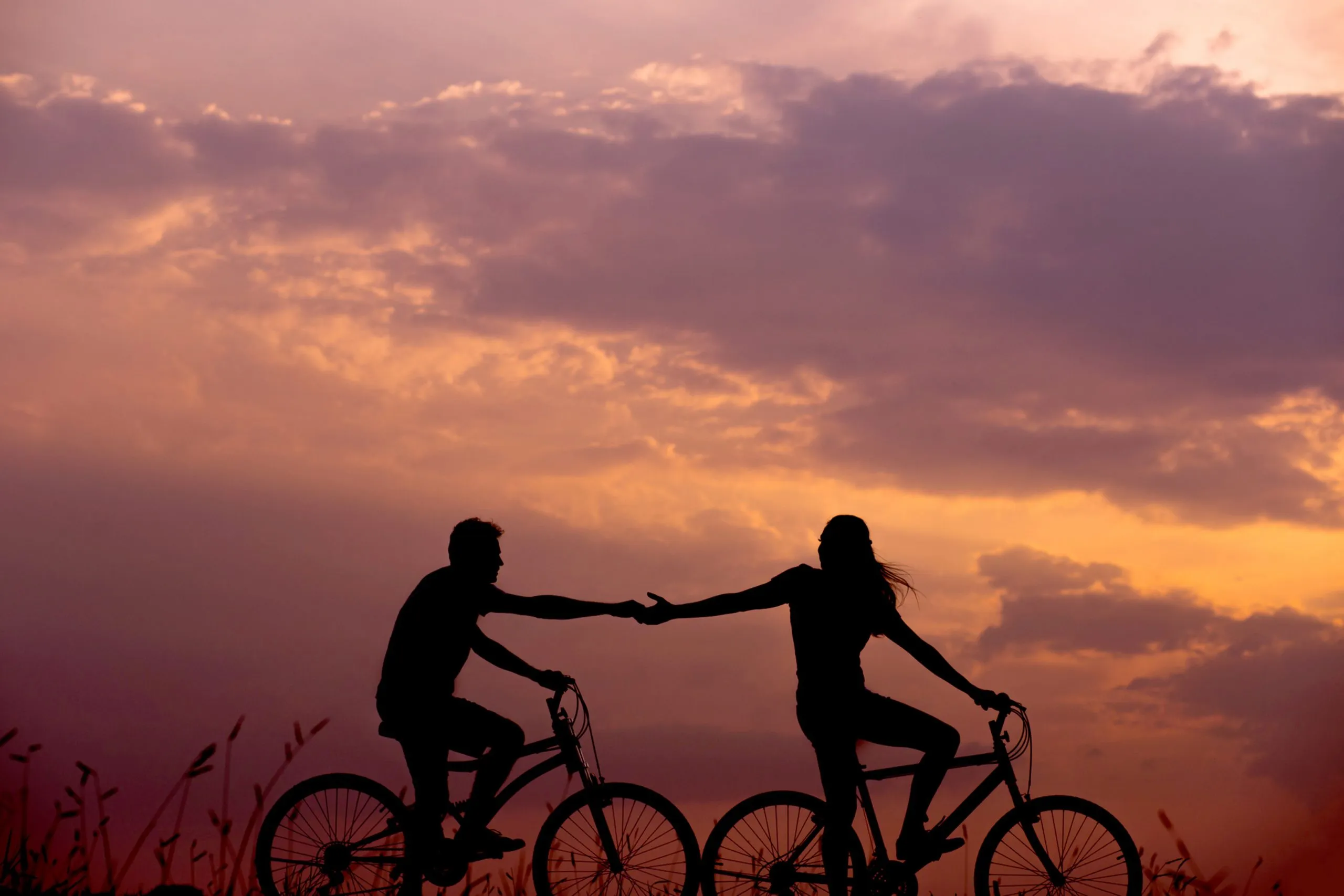 Silhouette of a happy couple cycling together against a horizen backdrop