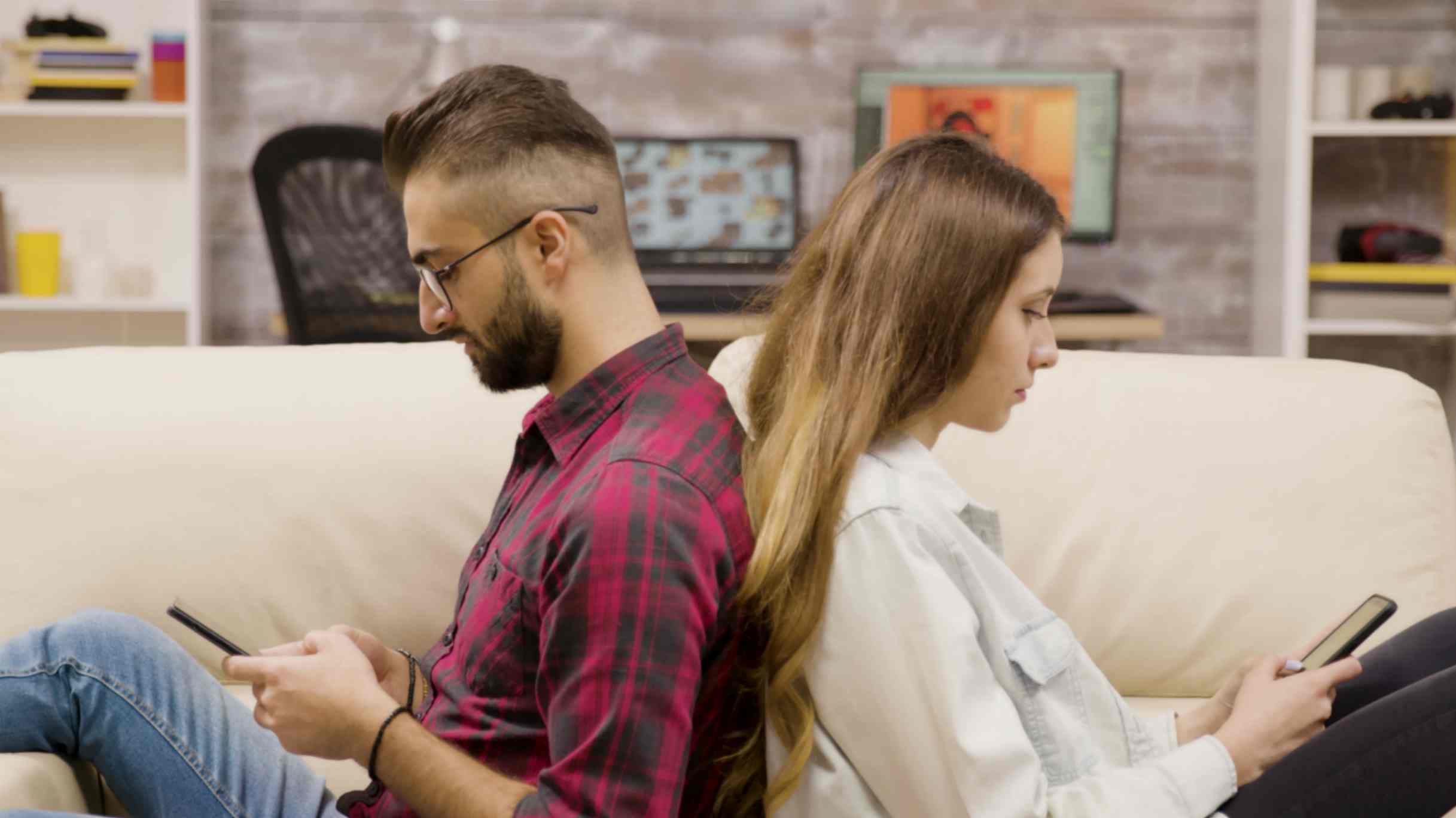 Upset Couple Sitting Against Each Other and Using Phone