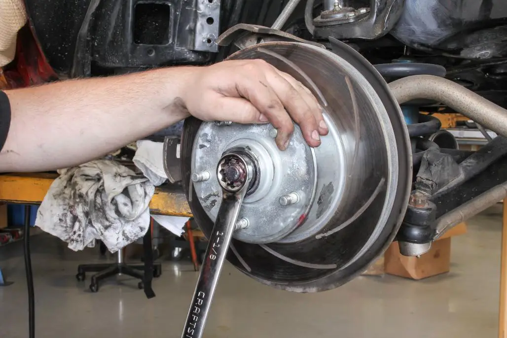 A man expertly unfastening a wheel bearing nut.
