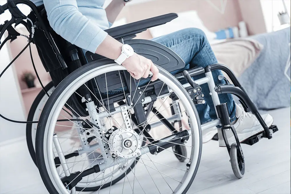 A side view of a woman sitting in a wheelchair with her hand on the wheel