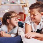 Brother and sister talking with each other, while lying in their playroom