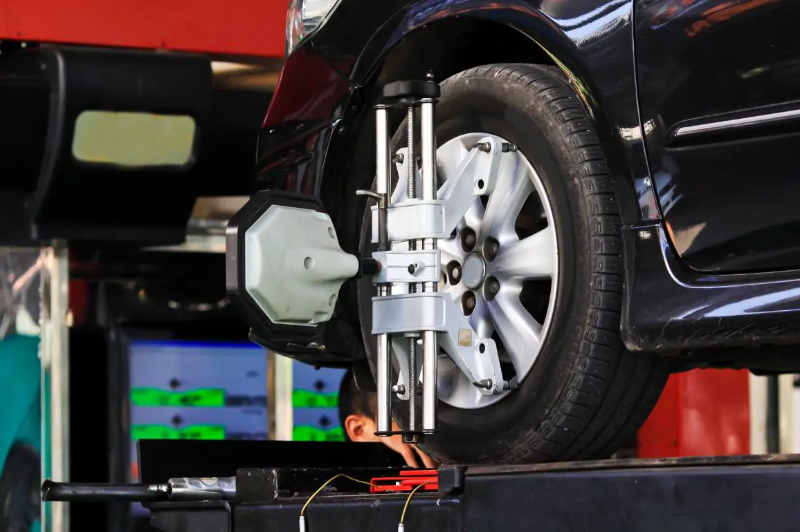 Auto repair shop performing a wheel alignment with a partially visible mechanic's head