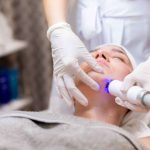 Woman lying on dermatology bed going through light therapy for rosacea
