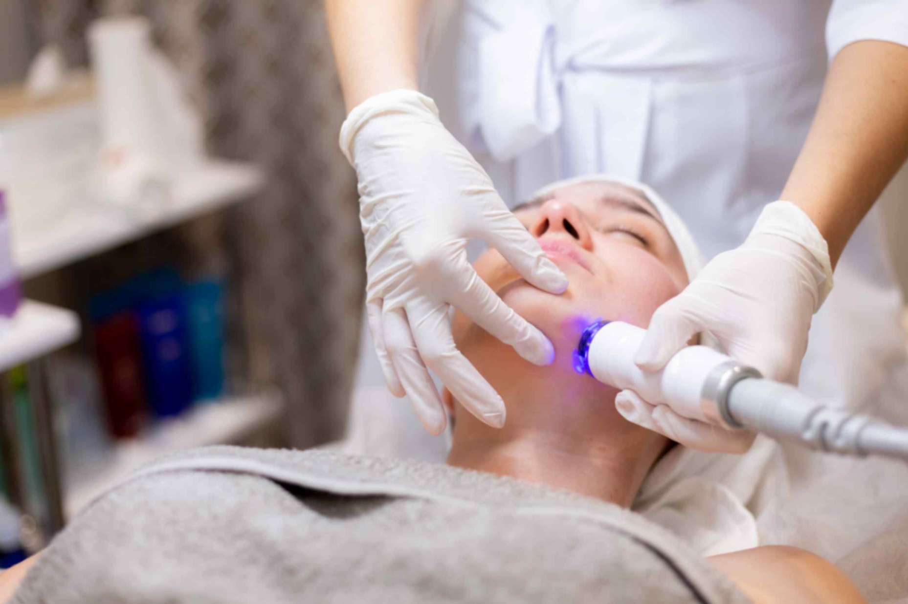 Woman lying on dermatology bed going through light therapy for rosacea