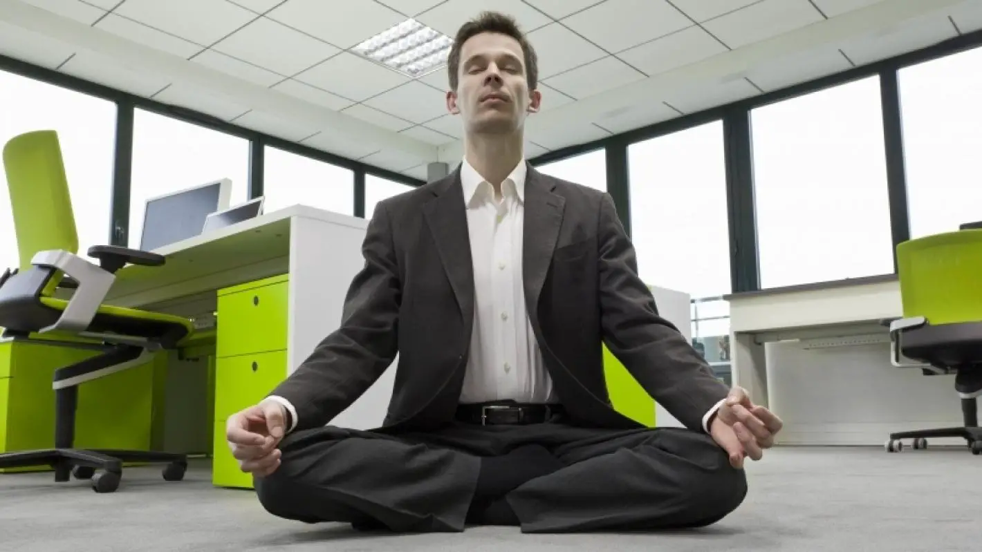 A man meditating in an office environment