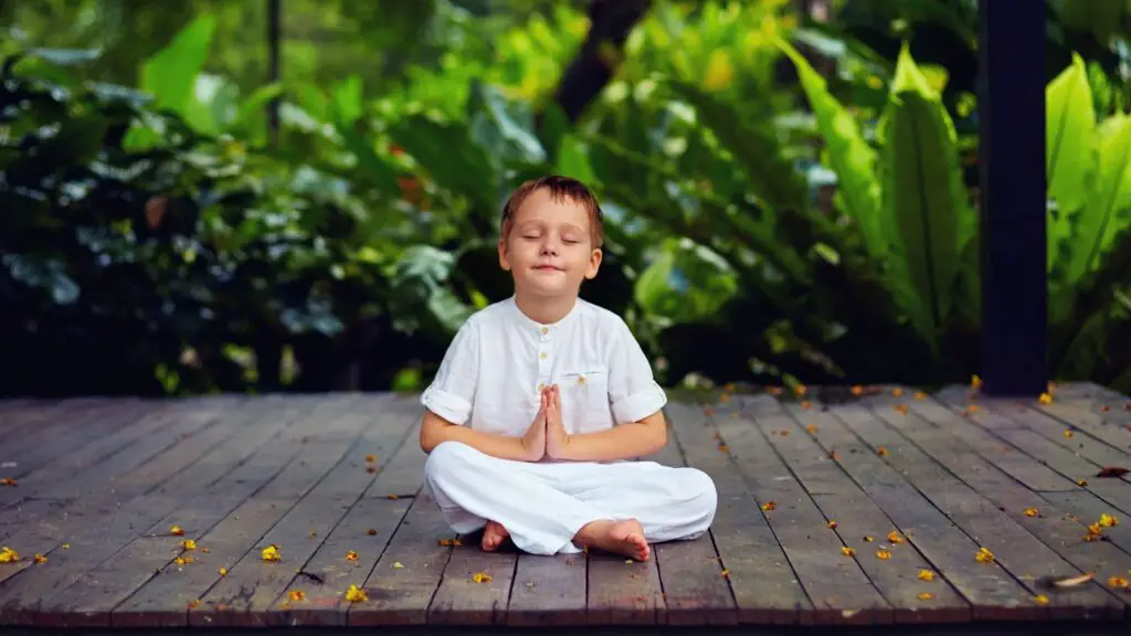 A child meditating on a wooden floor 