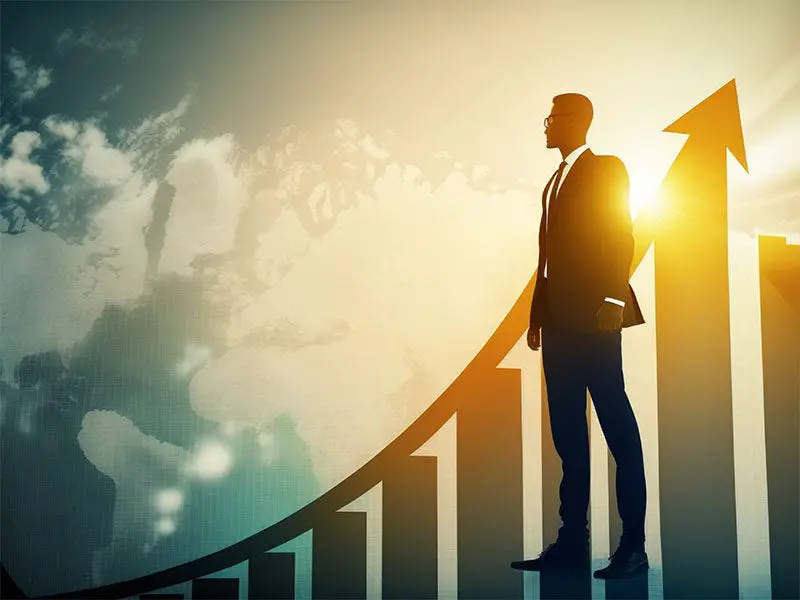 Silhouette of a tall figure standing confidently against a rising graph symbolizing personal growth and development.