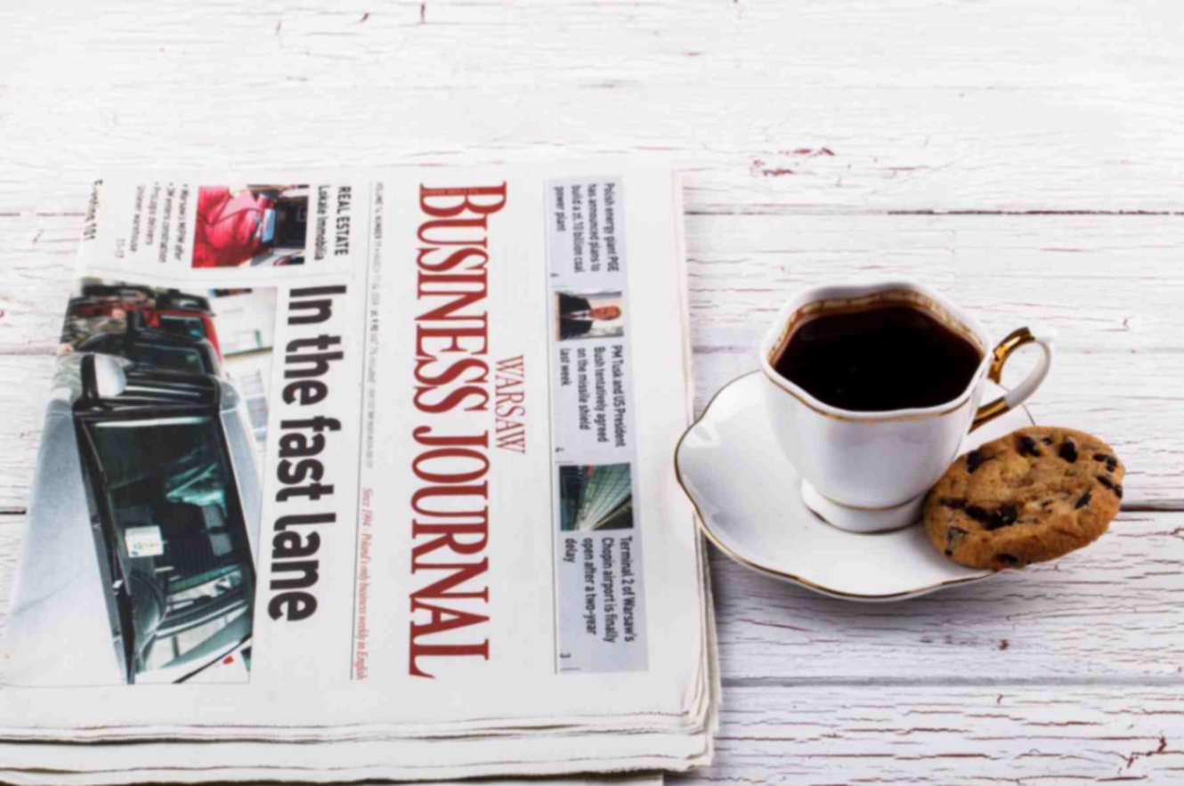 Porcelain cup with coffee and newspapers on table