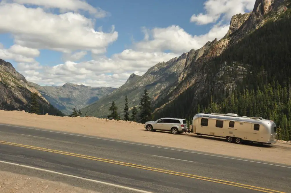 A Large Vehicle Hauling Heavy Loads Uphill Through Stunning Mountain Landscapes