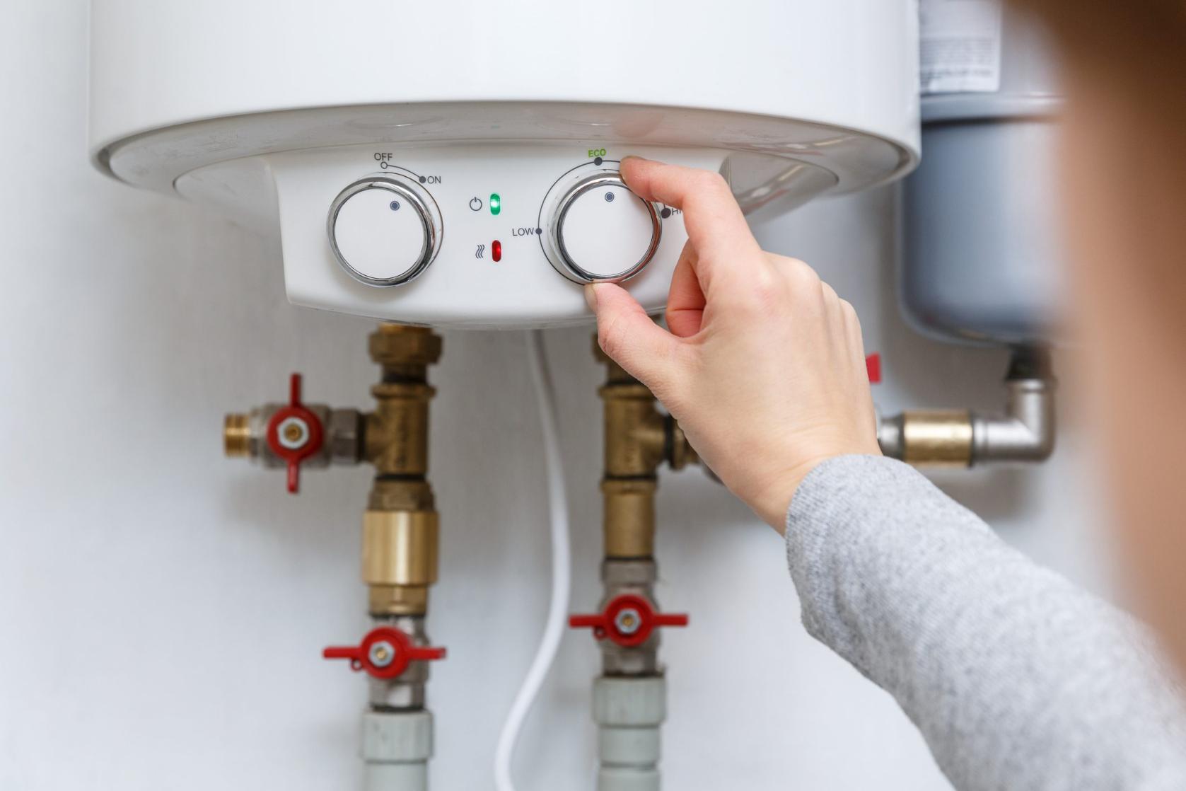 A person adjusting the knob of a water heater