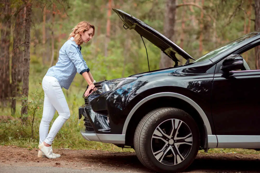 worried woman standing by malfunctioned car