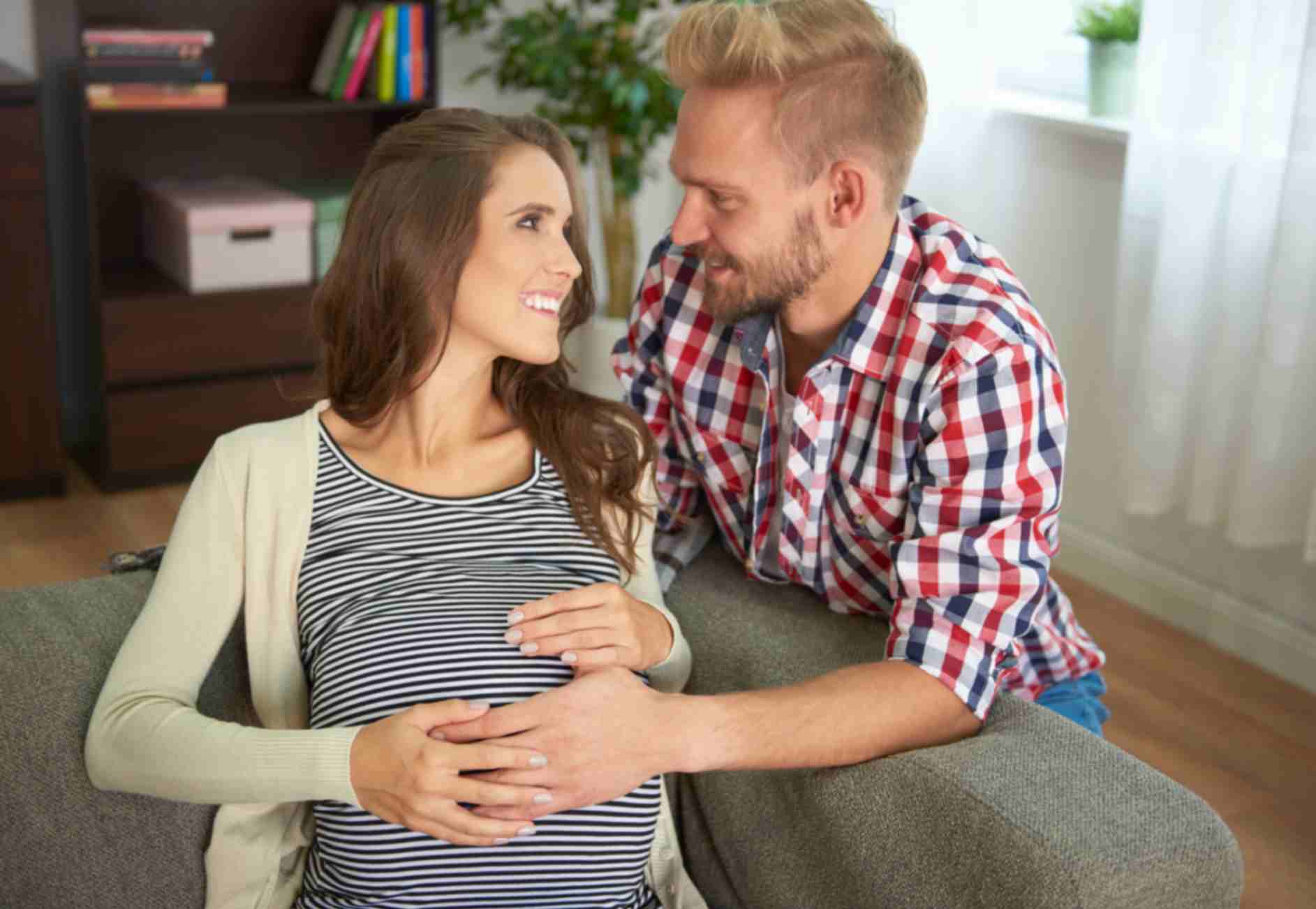 A pregnant woman and his husband sitting on sofa