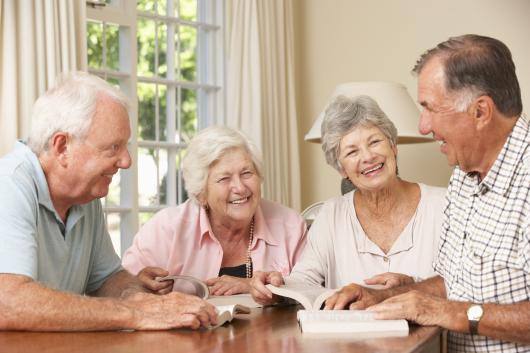 Elderly People sitting together and reading in a library