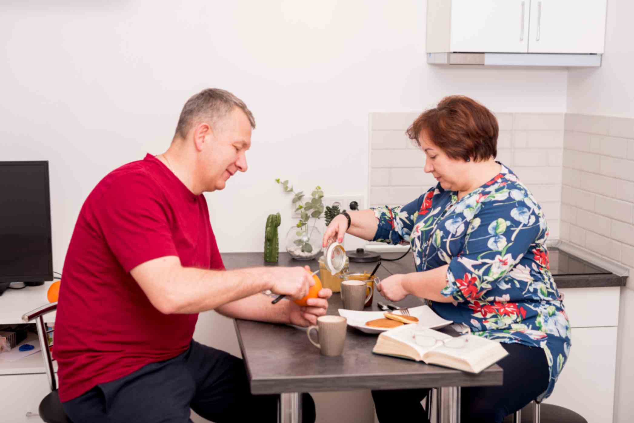 Elderly couple sitting in the kitchen preparing breakfast