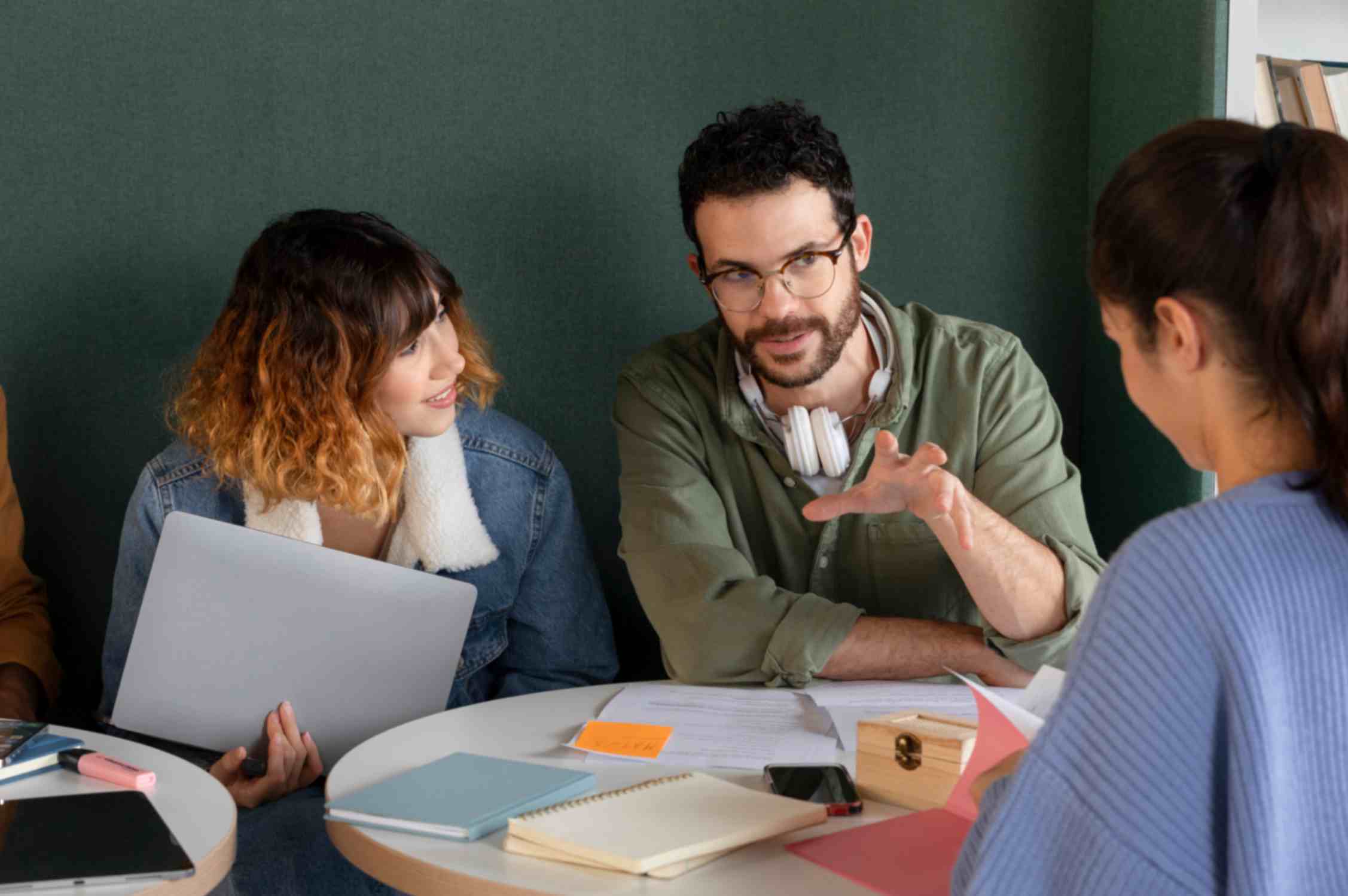 Friends discussing and studying from notebook and laptop during study session