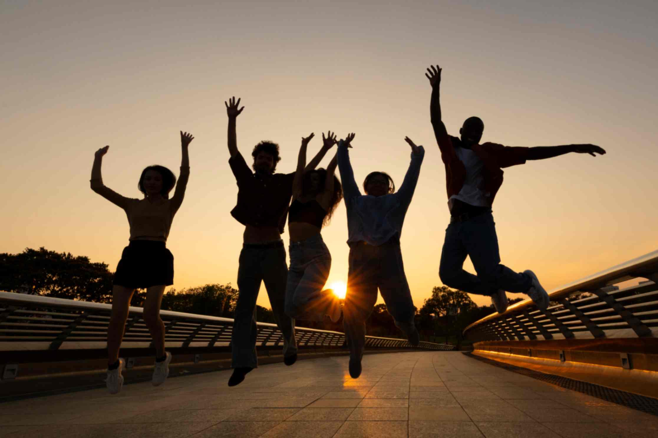 Full shot of friends jumping with sun setting behind