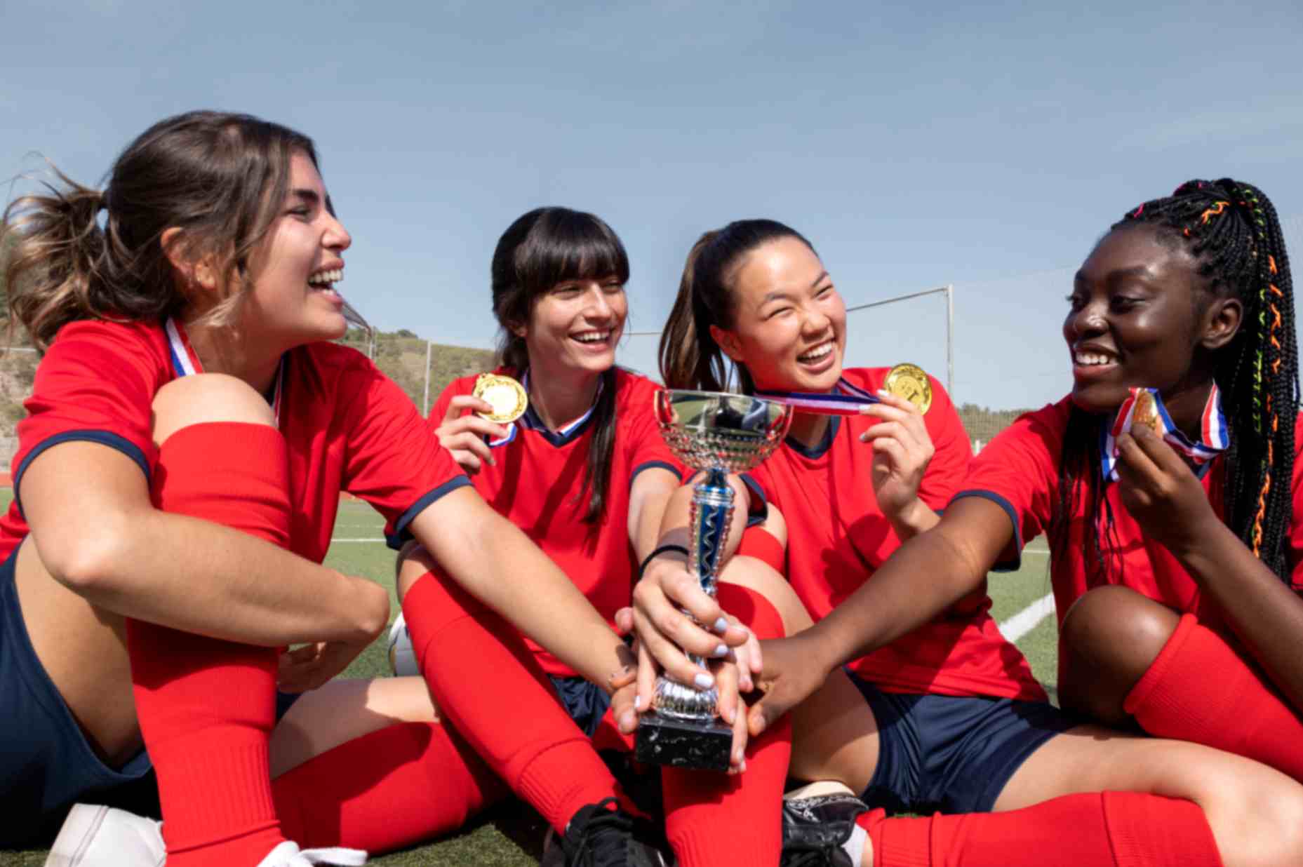 Girls celebrating their win in sports holding-cup and wearing medals