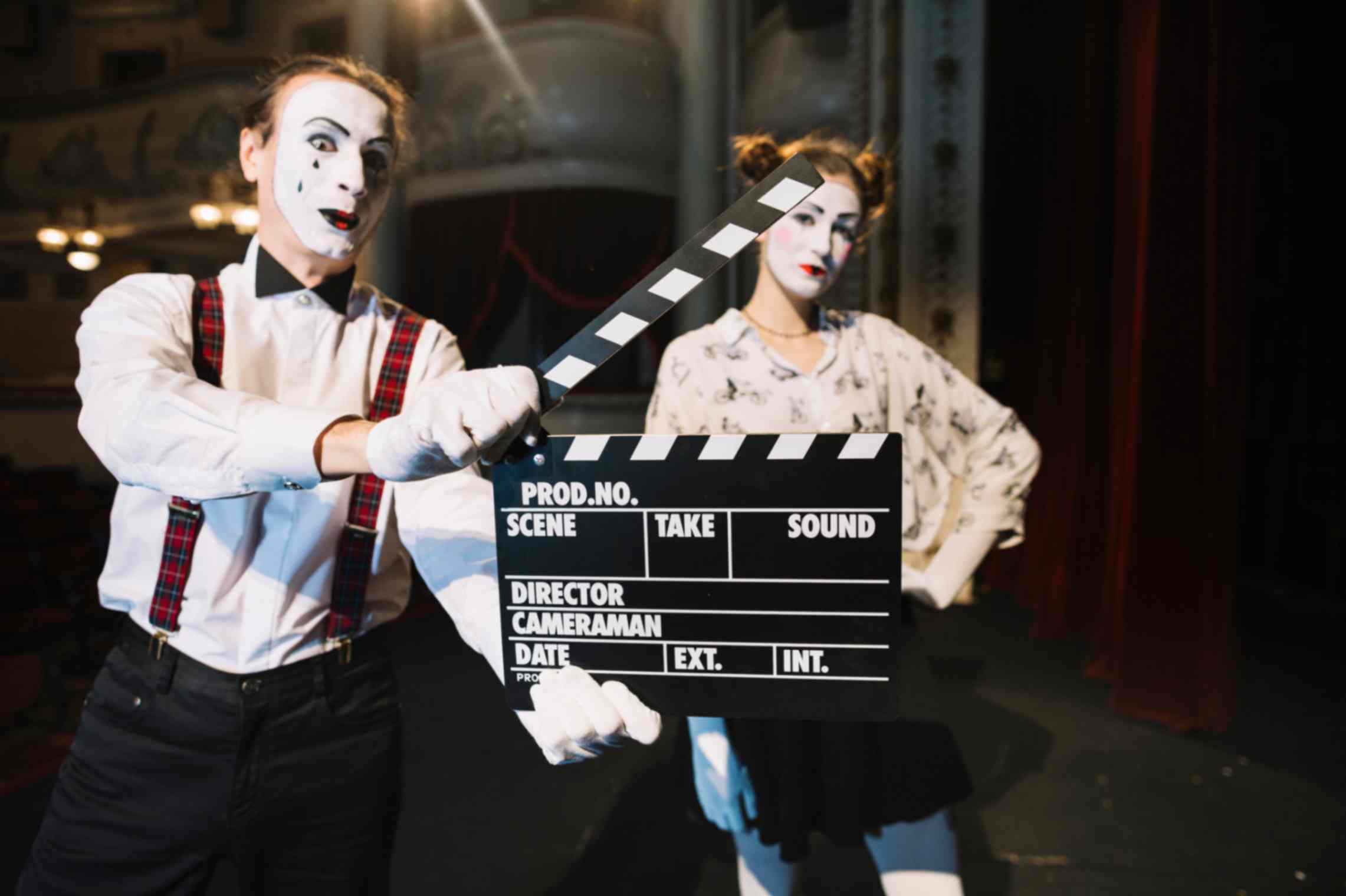 Male mime artist holding clapper front female mime artist