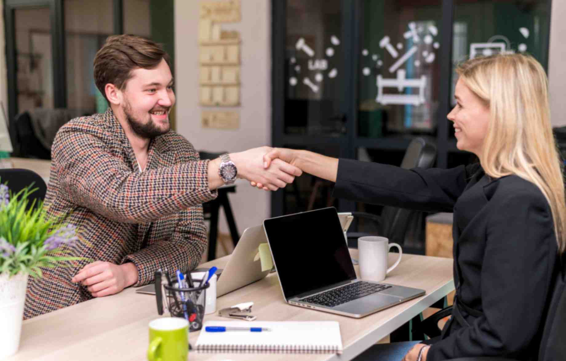 Man and woman shaking hands after signing deal at work