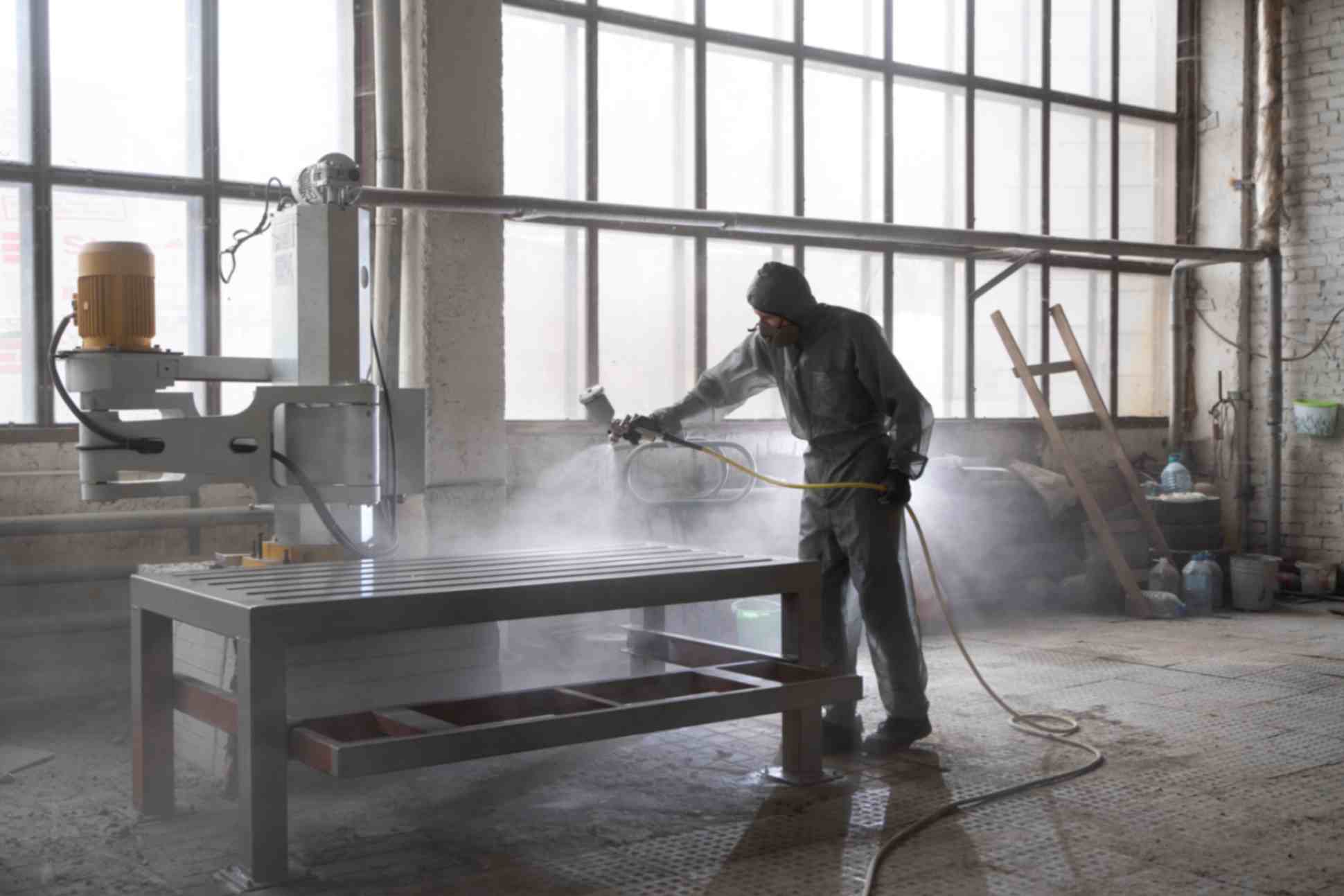 Man spraying powder paint from gun 
