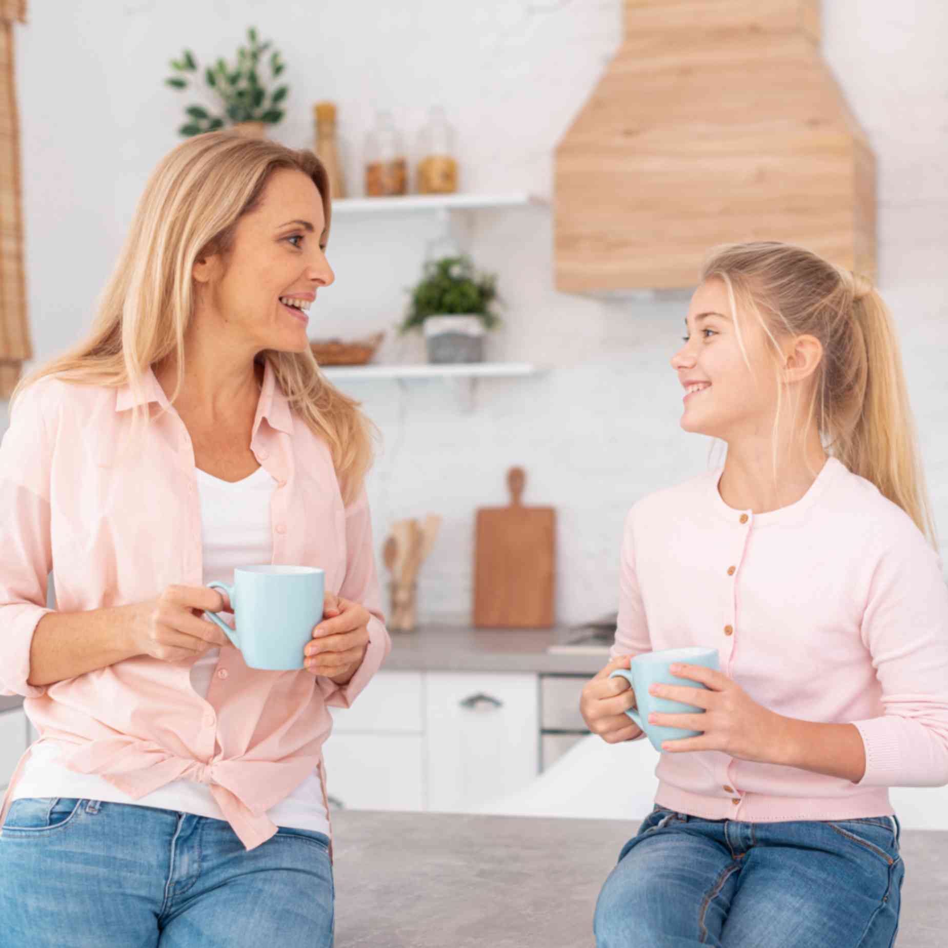 Mother and daughter holding mugs talking to each other