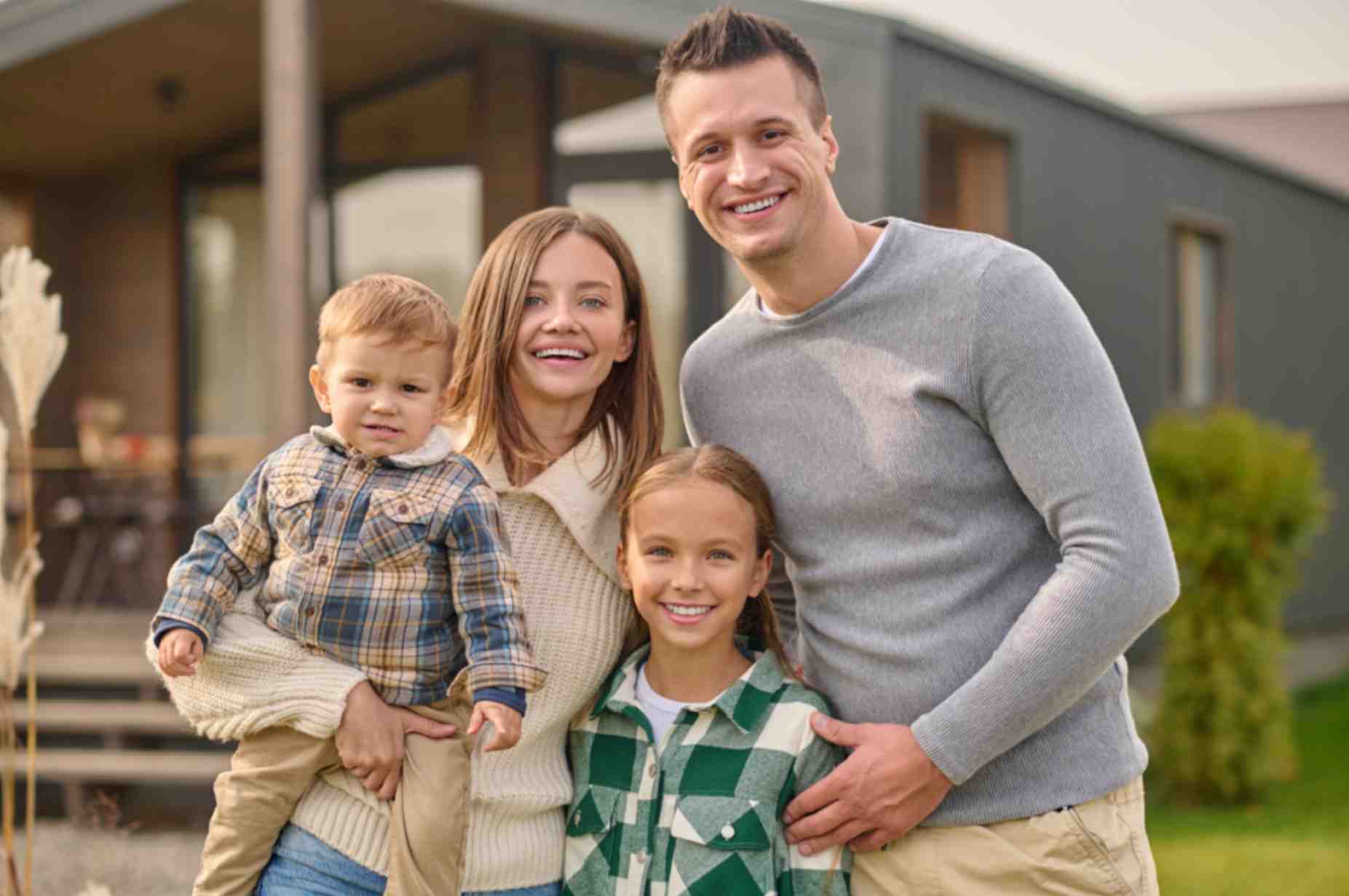 Parents with their kids posing for a photo outside their home - family portrait